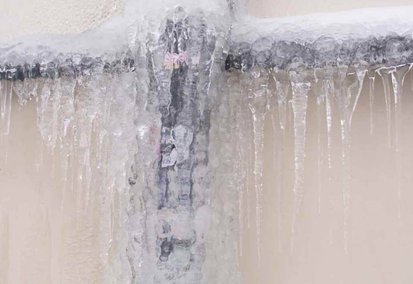 Frozen pipe covered in ice during winter